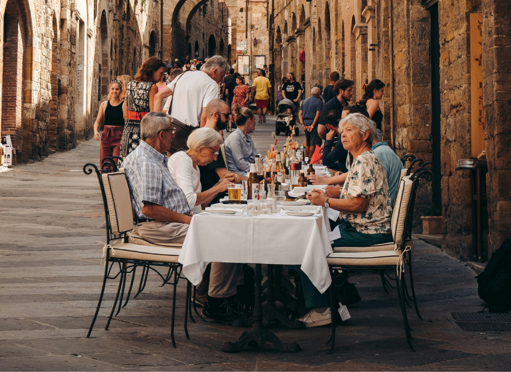 a tight italian alley with people eating outside at tables